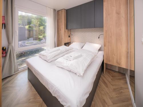 a bedroom with a bed with white sheets and a window at Romantic Tiny House for Two – Resort Walsdorf in Fouhren