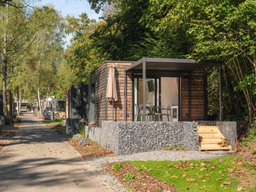 een kleine hut met een stenen muur naast een trottoir bij Tiny House | 2 personen in Tandel