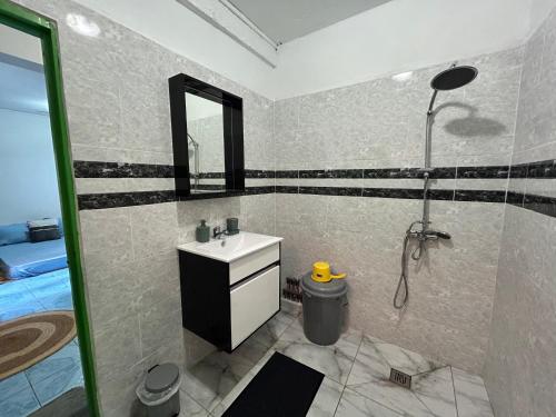a bathroom with a sink and a shower with a mirror at steila-Day hébergement chambre privée in Pamandzi