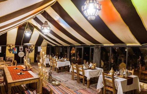 een eetkamer met tafels en stoelen in een tent bij Layalée Luxurycamp in Merzouga