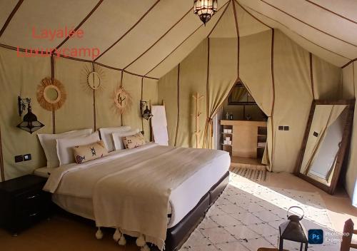 een slaapkamer met een groot bed in een tent bij Layalée Luxurycamp in Merzouga