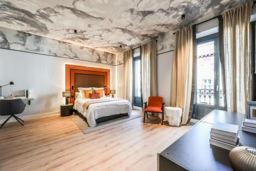 a bedroom with a bed and a painting of clouds on the ceiling at AmazINN Collection Madrid Plaza Mayor in Madrid