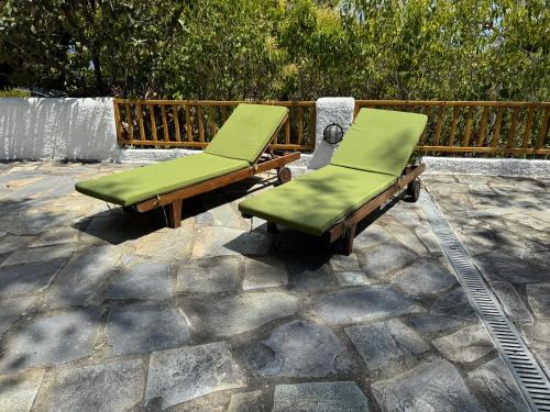 two green lounge chairs sitting on a stone patio at Villa Anna in Kalamos