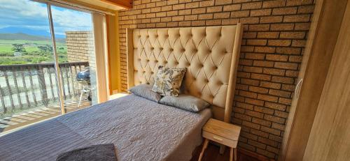 a bed in a room with a brick wall at Mountain View in Klein Brak Rivier