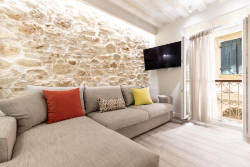 a living room with a couch and a stone wall at Petite Town Hall Apartment by Konnect, Old Corfu Town in Corfu Town