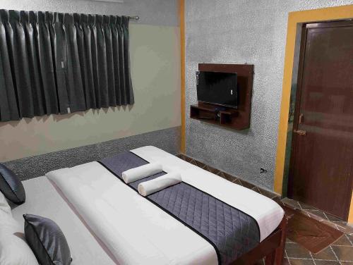 a bedroom with a bed and a tv in it at Misty Valley Inn in Kodaikānāl
