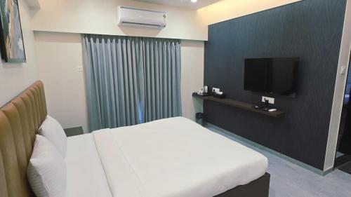 a hotel room with a bed and a television at Hotel The Golden Oaks, Kolhapur in Kolhapur