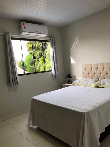 a bedroom with a large bed and a window at Alphaville Sobrado com Piscina e área Gourmet para 10 pessoas in Bonito