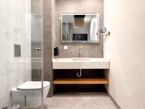 a bathroom with a sink and a toilet and a mirror at HAYASHI Boutique Apartments in Sofia