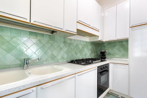 eine Küche mit weißen Schränken und einer Spüle in der Unterkunft Hostdomus-Villa Verde in Noli