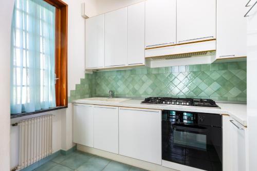 eine Küche mit weißen Schränken und einem schwarzen Geschirrspüler in der Unterkunft Hostdomus-Villa Verde in Noli