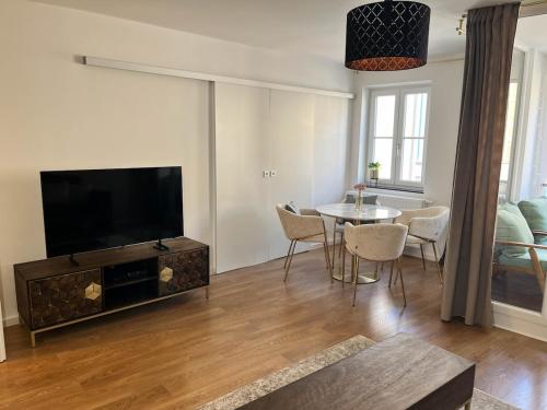 a living room with a tv and a table with chairs at City Quartier 4 Traumlage Augsburg Zentrum in Augsburg