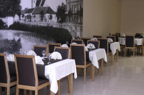 a row of tables and chairs with white table cloths at Rooms Virovitica in Virovitica