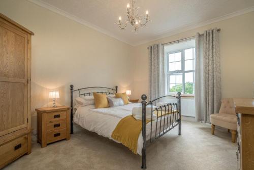 a bedroom with a bed and a chandelier and a window at Ficerdy in Llanwnda