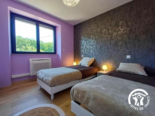 a bedroom with two beds and a purple wall at L'Escapade in Gagnac