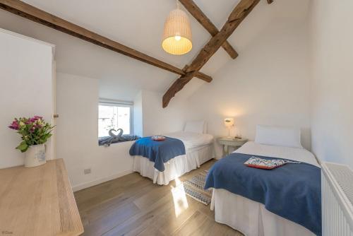 twee bedden in een kamer met houten balken bij Bwthyn-Bennar in Dyffryn