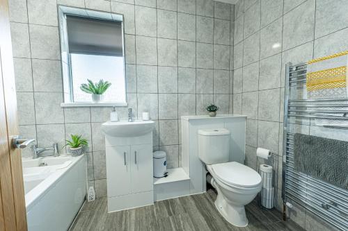 Un baño blanco con inodoro y lavabo. en Stunning 4-Bed Beachfront Home Sea Views in Dymchurch, en Dymchurch