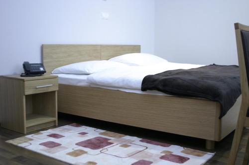 a bed with a wooden headboard and a night stand with a phone at Rooms Virovitica in Virovitica