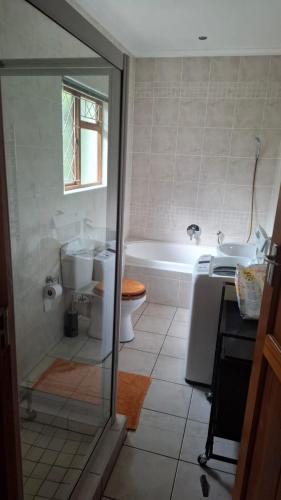 a bathroom with a tub and a toilet and a sink at The Cottage, Heide Avenue in Somerset West