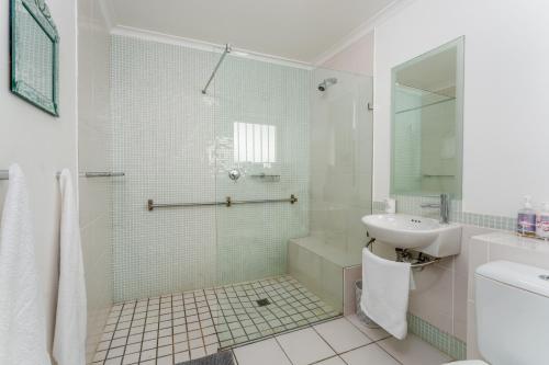 a white bathroom with a sink and a shower at Spectacular views Simonstown in Cape Town