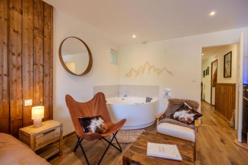a living room with a tub and a chair at L'Ostalet suite luxe Jacuzzi in Ax-les-Thermes