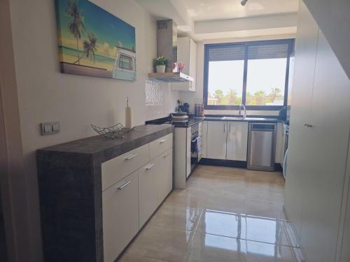 a kitchen with white cabinets and a large window at Cozy, modern, two-level apartment in Orihuela Costa