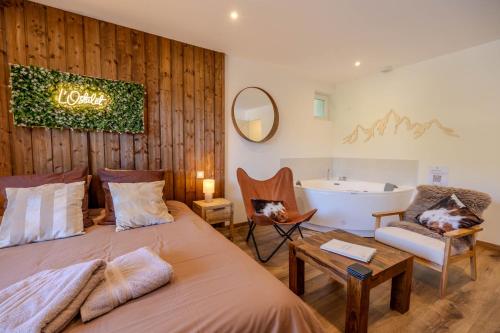 a bedroom with a bed and a tub and a chair at L'Ostalet suite luxe Jacuzzi in Ax-les-Thermes