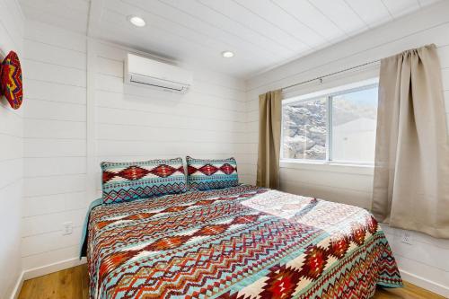 a bedroom with a bed with a comforter and a window at Trails & Tranquility in Pagosa Springs