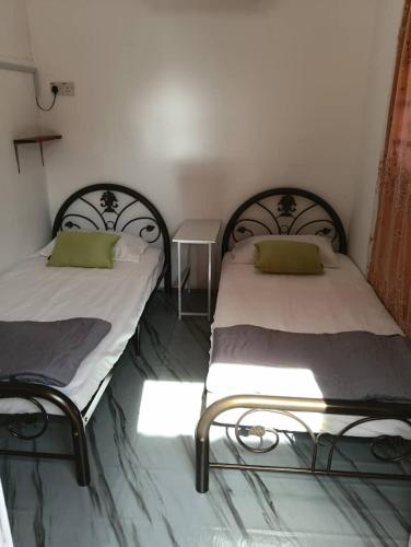 deux lits côte à côte dans une pièce dans l'établissement Debunga Chalet, à Teluk Bahang