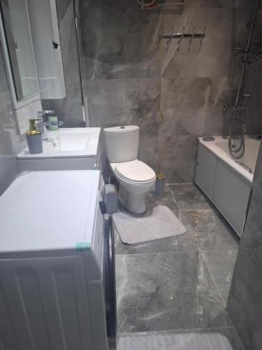 a bathroom with a toilet and a sink and a tub at Квартира в центре города in Dushanbe