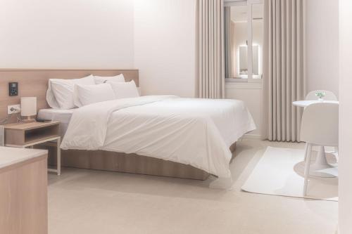 a white bedroom with a large bed and a table at 인별호텔 in Suncheon