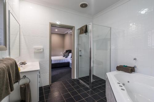 a bathroom with a shower, sink, and toilet at Akuna Motor Inn and Apartments in Dubbo