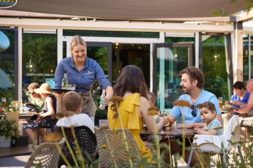 Una mujer parada frente a un grupo de personas en un restaurante. en RCN Vakantiepark de Roggeberg, en Appelscha
