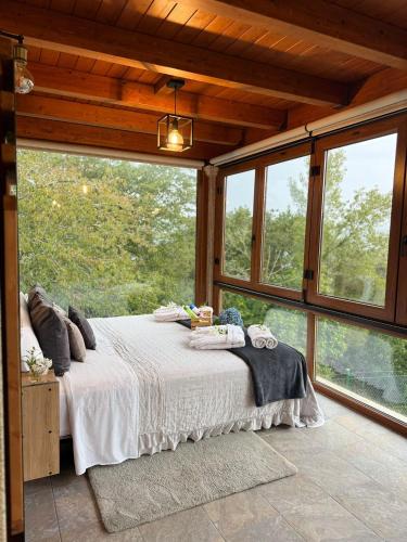 a bedroom with a bed in a room with windows at O MIRADOR da RÍA in Outes