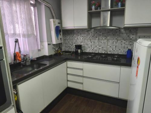 a kitchen with white cabinets and a stove top oven at Apartamento aconchegante 10 minutos de Penedo in Resende