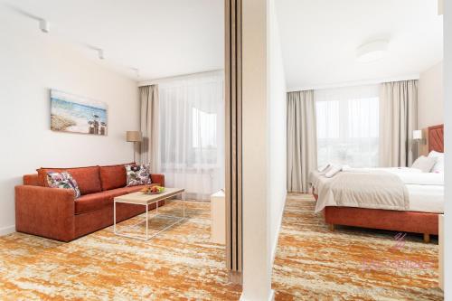 a living room with a couch and a bed and a mirror at Your Holidays Komfortowy Apartament Bel Mare 213 F, Parking Gratis in Międzyzdroje
