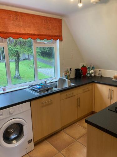 a kitchen with a sink and a washing machine at Sue's Lodge in Cawsand