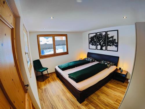 a bedroom with a large bed and a chair at Chasa Salnuun Ferienwohnungen in Samnaun