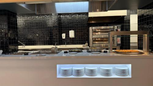 una cucina con bancone e piatti bianchi di AQUA Hotel Bertran Park a Lloret de Mar