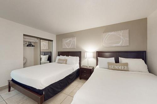 two beds in a hotel room with white sheets at Ocean Vista #102 in South Padre Island