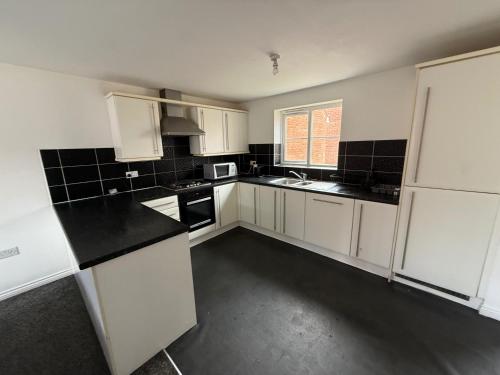 eine leere Küche mit weißen Schränken und schwarzen Arbeitsplatten in der Unterkunft Charming Aylesbury Retreat with 4 Bedrooms in Weedon