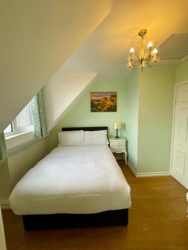 a bedroom with a white bed with a chandelier at Shandon Bells Guest House in Cork