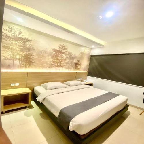 a bedroom with a bed and a painting on the wall at Front One Hotel Purwodadi in Purwodadi