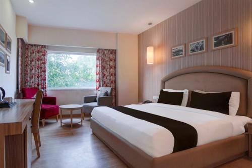 a hotel room with a large bed and a desk at Townhouse Oak Sahastradhara Road Dehradun in Dehradun