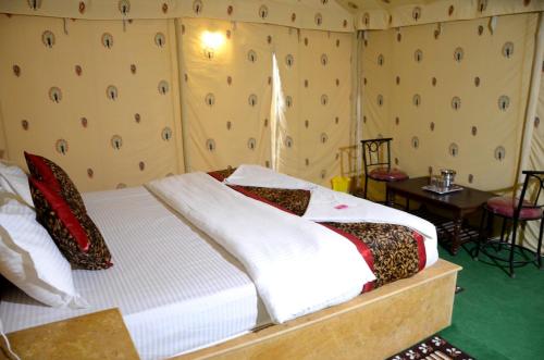a bedroom with a bed and a table and a window at White Thar Camp in Dhordo