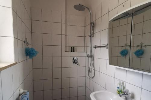 a white tiled bathroom with a shower and a sink at Ulm 2-room Apartment near university & city Centre in Ulm