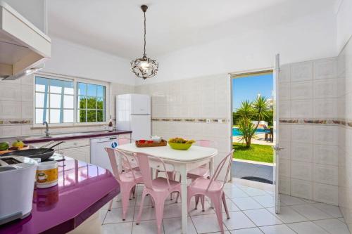 a kitchen with a white table and pink chairs at Villa Gale Palm by Villa Plus in Albufeira