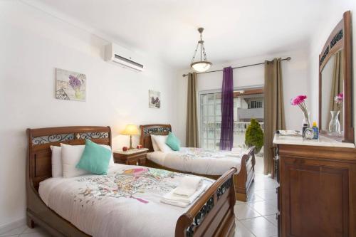 a bedroom with two beds and a window at Villa Gale Palm by Villa Plus in Albufeira
