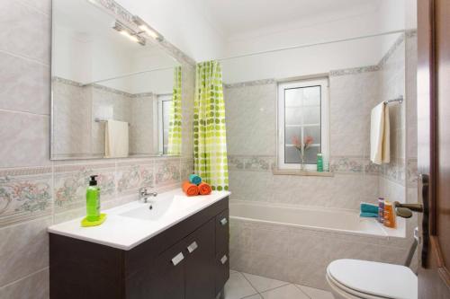 a bathroom with a sink and a tub and a toilet at Villa Gale Palm by Villa Plus in Albufeira