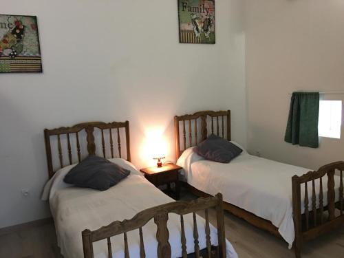 two beds in a room with a lamp on a table at L'ammonite in Chaunay